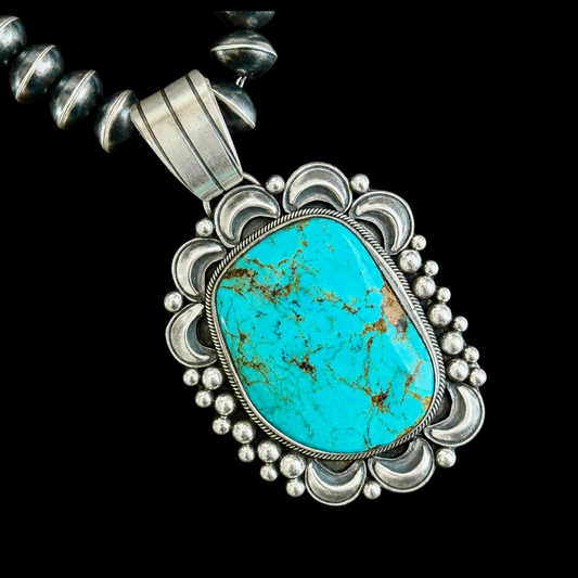 Turquoise pendant with silver frame on a black background