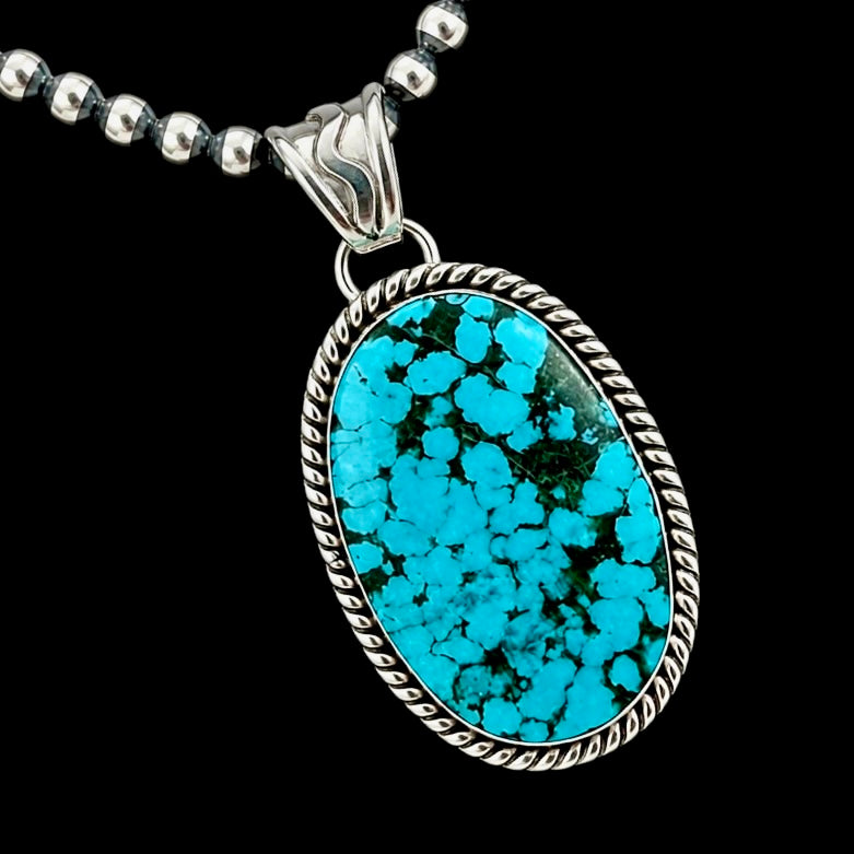 Turquoise pendant necklace on a black background by Sheena Jack