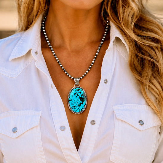 Turquoise pendant necklace on a black background by Sheena Jack